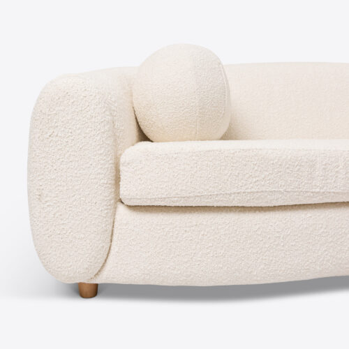 curved sofa in boucle with pink ball cushion