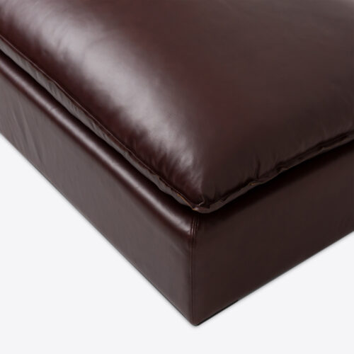 dark brown leather armless sofa with oblong leather bolster cushions